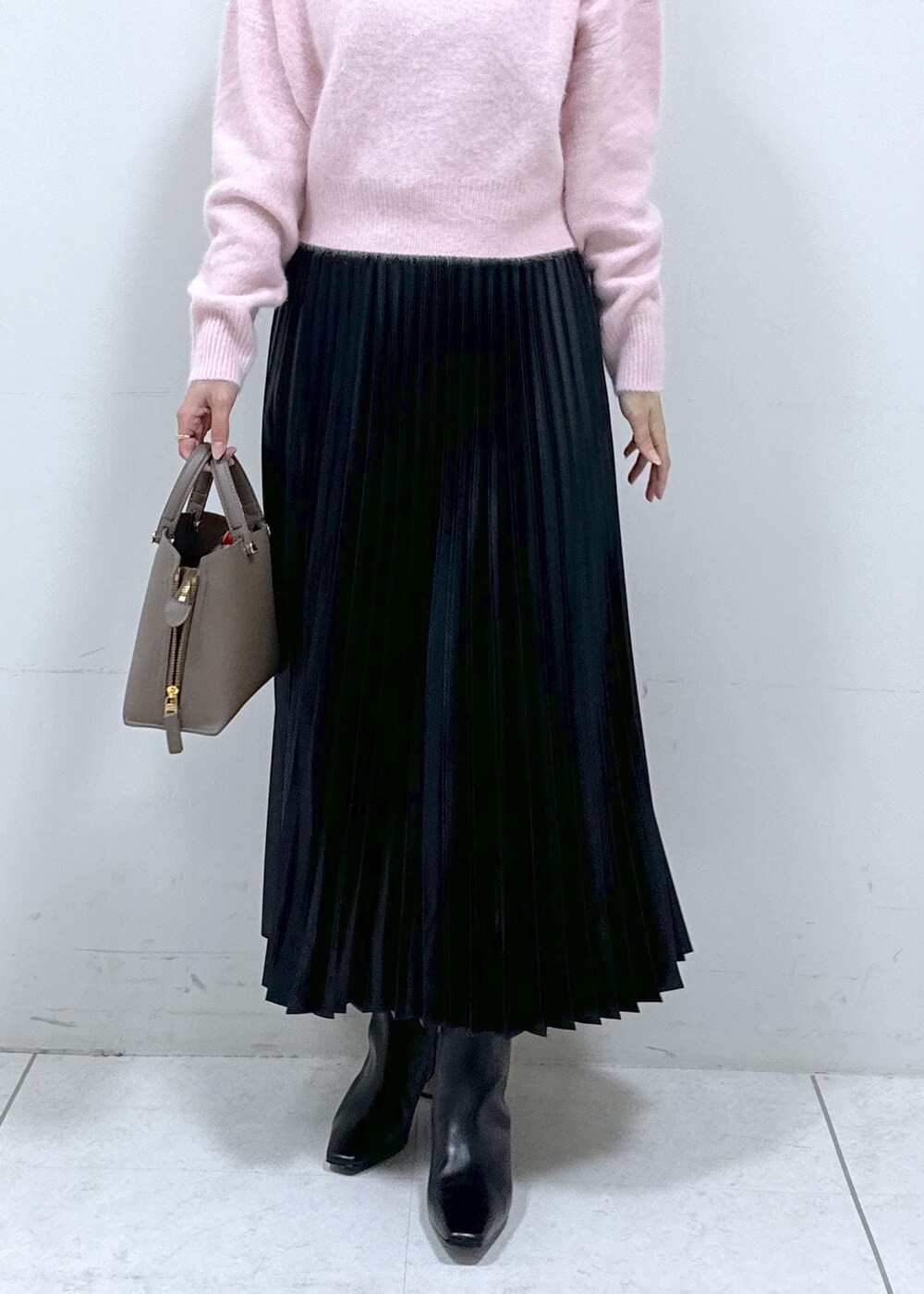 ブラック系のブーツ、ブラウン系のハンドバッグ、ホワイト系のステンカラーコートを着用したレディースの秋コーディネートの7枚目の写真