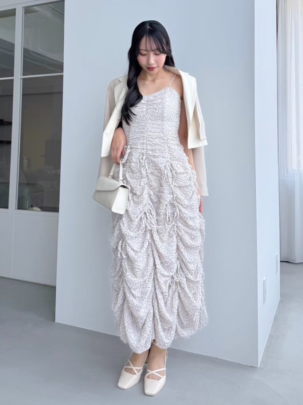 ピンク系のワンピース、ホワイト系のテーラードジャケットを着用したレディースの冬コーディネートの2枚目の写真