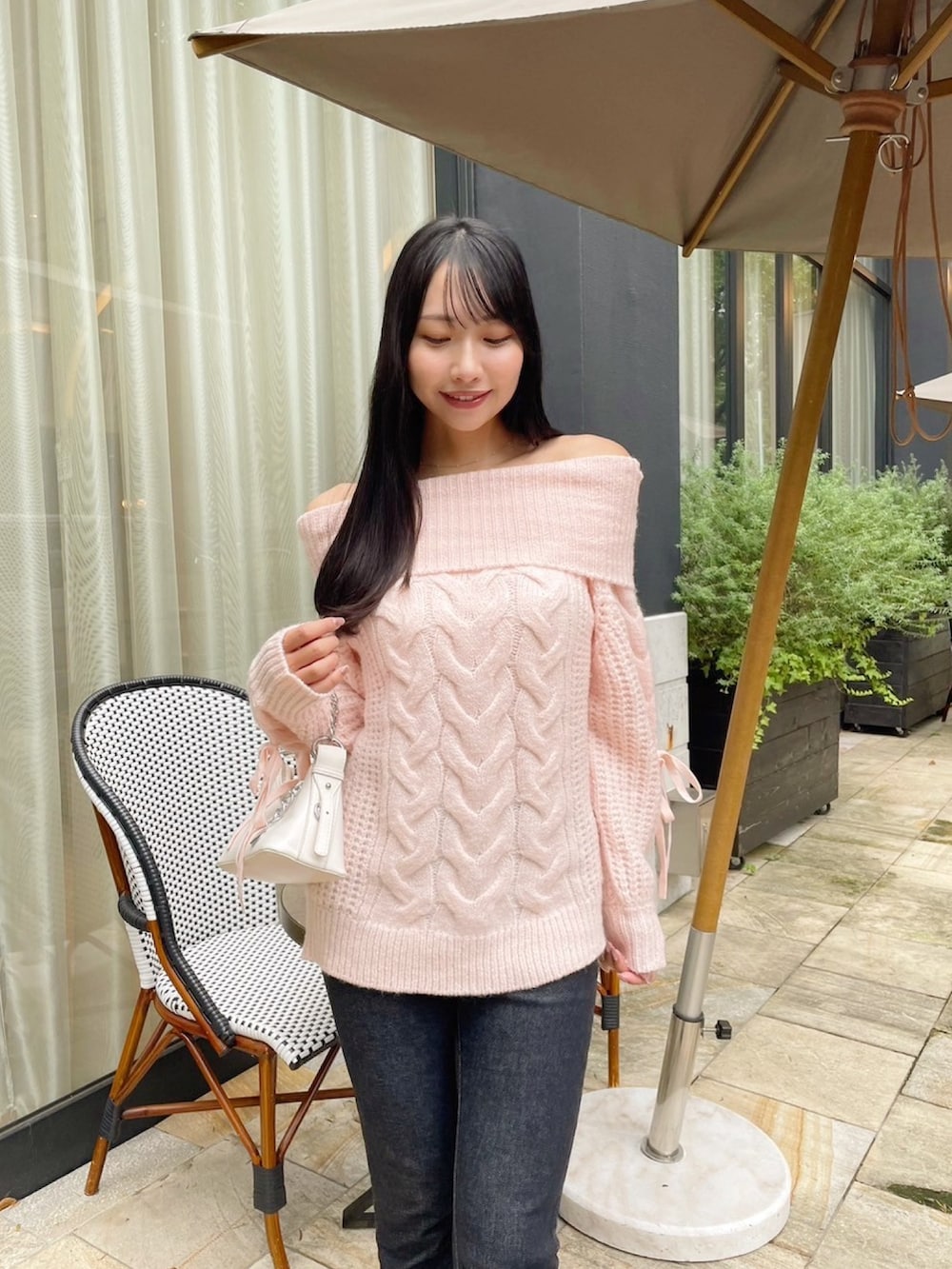 ピンク系のニット/セーター、ブルー系のデニムパンツを着用したレディースの秋コーディネートの2枚目の写真