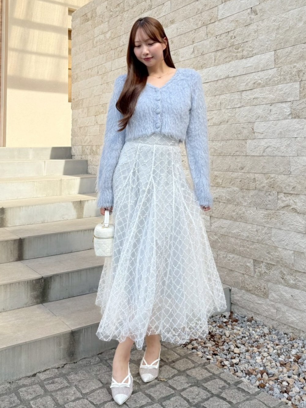 グレー系のスカート、ブルー系のカーディガン/ボレロを着用したレディースの秋コーディネートの2枚目の写真