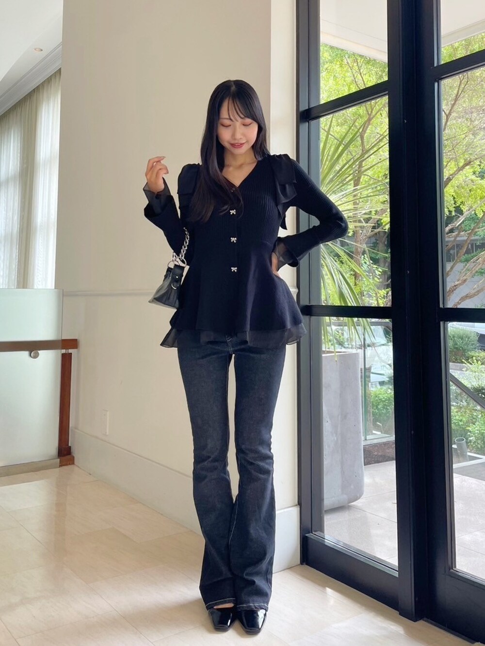 ブラック系のデニムパンツ、ブラック系のニット/セーター、ホワイト系のその他アウターを着用したレディースの秋コーディネートの2枚目の写真