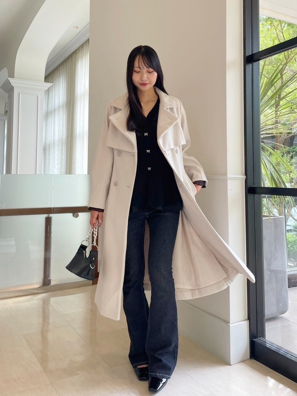 ブラック系のデニムパンツ、ブラック系のニット/セーター、ホワイト系のその他アウターを着用したレディースの秋コーディネートの3枚目の写真