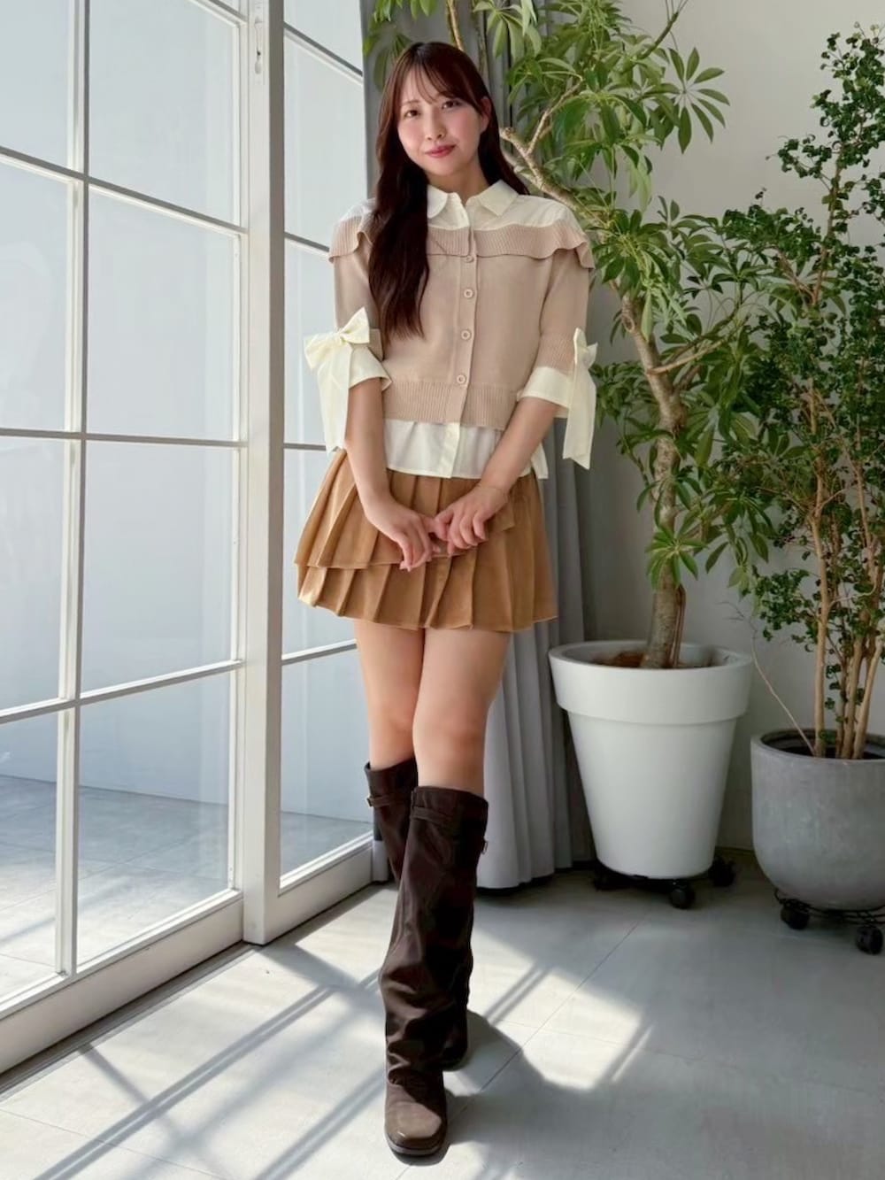 イエロー系のスカート、ベージュ系のニット/セーター、ブラウン系のブーツを着用したレディースの夏コーディネートの2枚目の写真