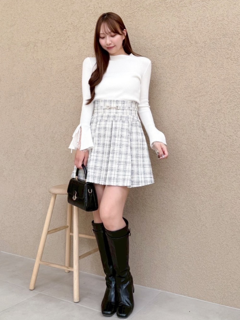 ホワイト系のニット/セーター、ホワイト系のスカート、ブラック系のブーツを着用したレディースの冬コーディネートの3枚目の写真