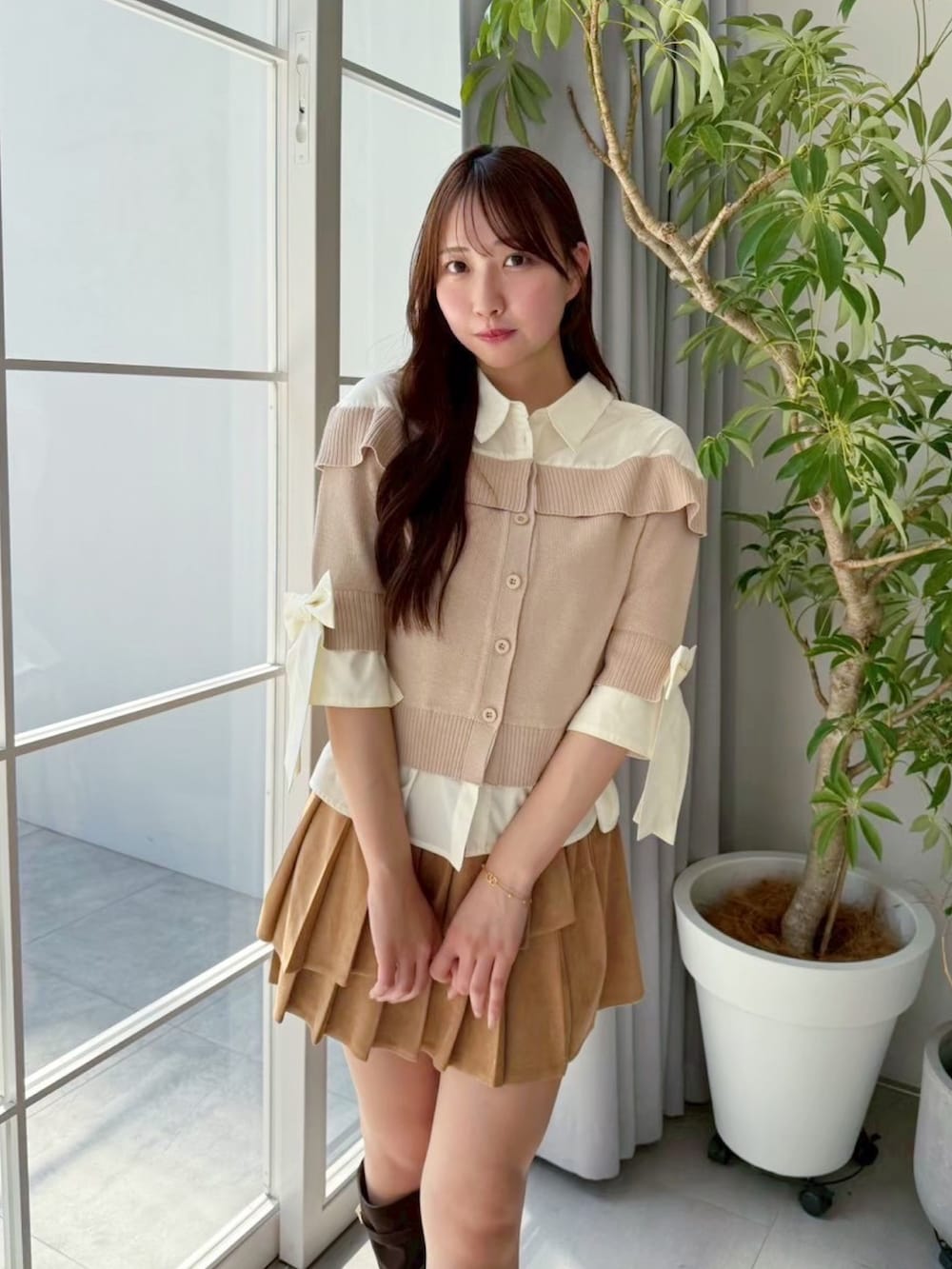 イエロー系のスカート、ベージュ系のニット/セーター、ブラウン系のブーツを着用したレディースの夏コーディネートの3枚目の写真