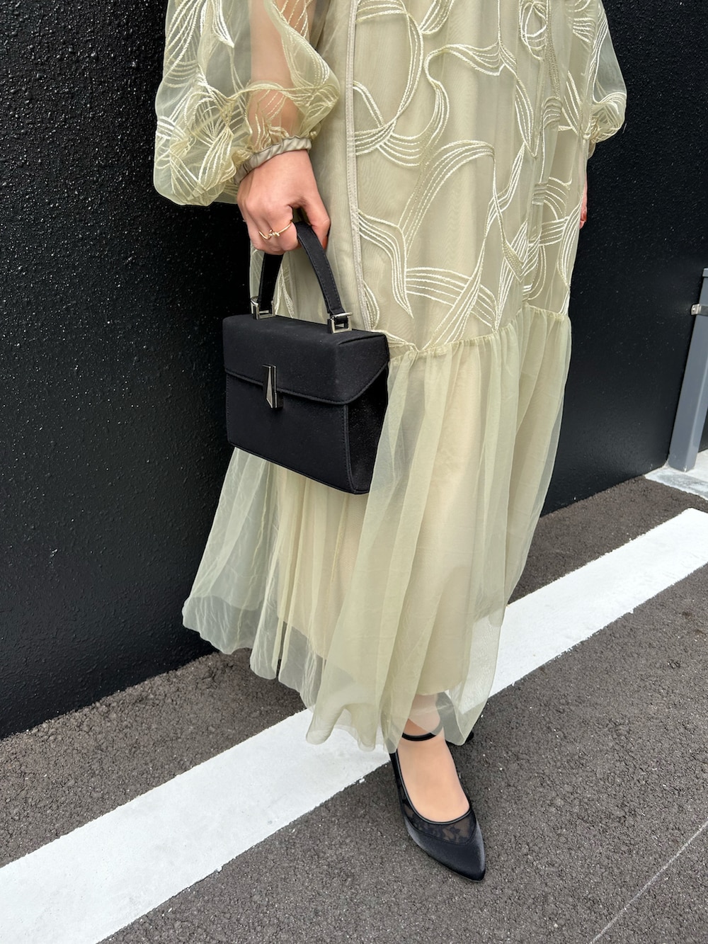 グリーン系のドレス、ブラック系のハンドバッグ、ブラック系のパンプスを着用したレディースの冬コーディネートの4枚目の写真