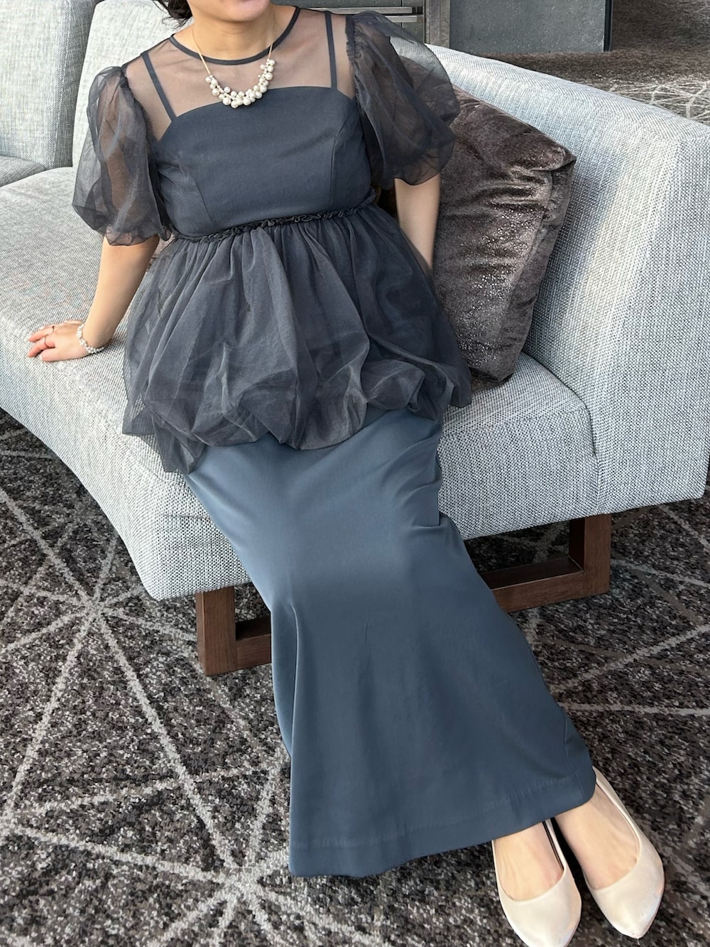 グレー系のドレス、シルバー系のクラッチバッグ、ベージュ系のパンプスを着用したレディースの冬コーディネートの4枚目の写真