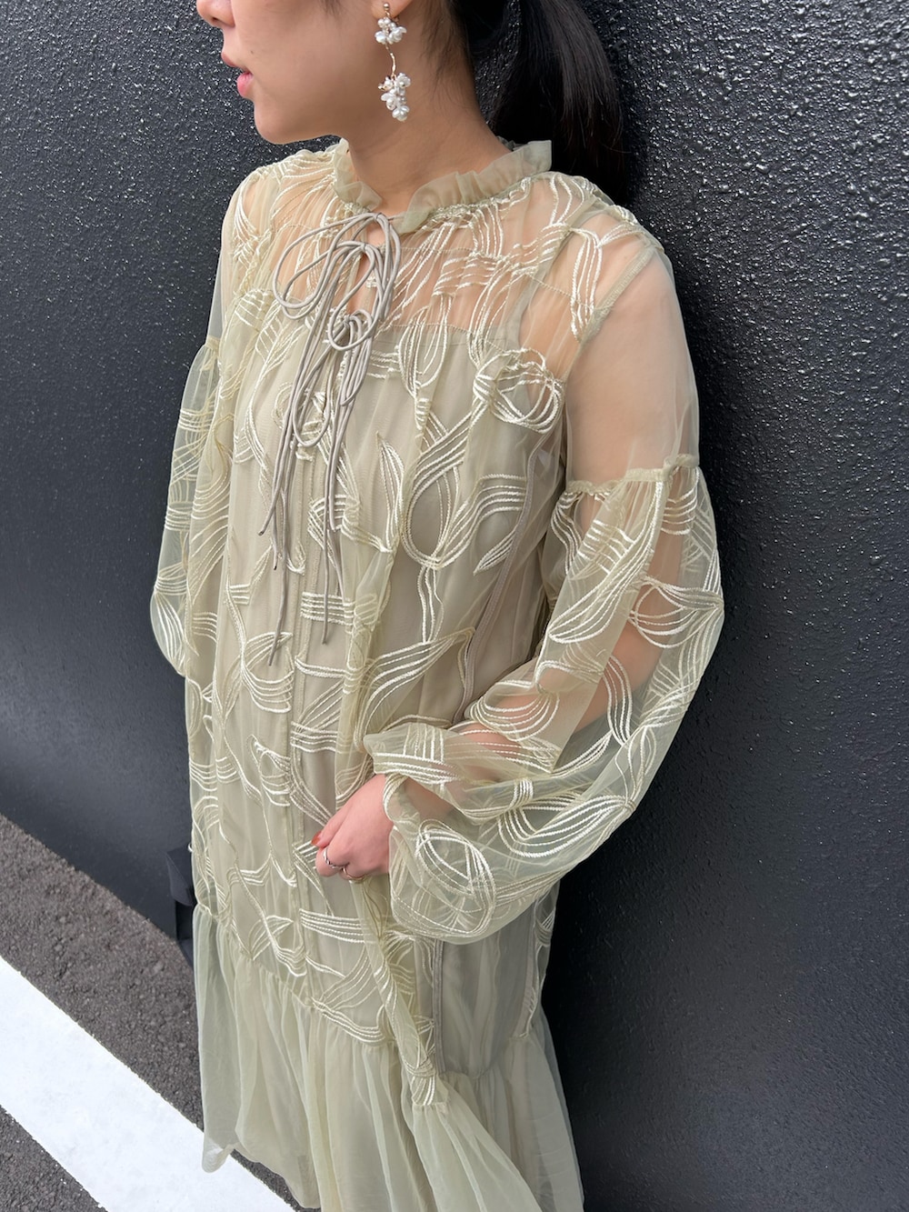 グリーン系のドレス、ブラック系のハンドバッグ、ブラック系のパンプスを着用したレディースの冬コーディネートの2枚目の写真