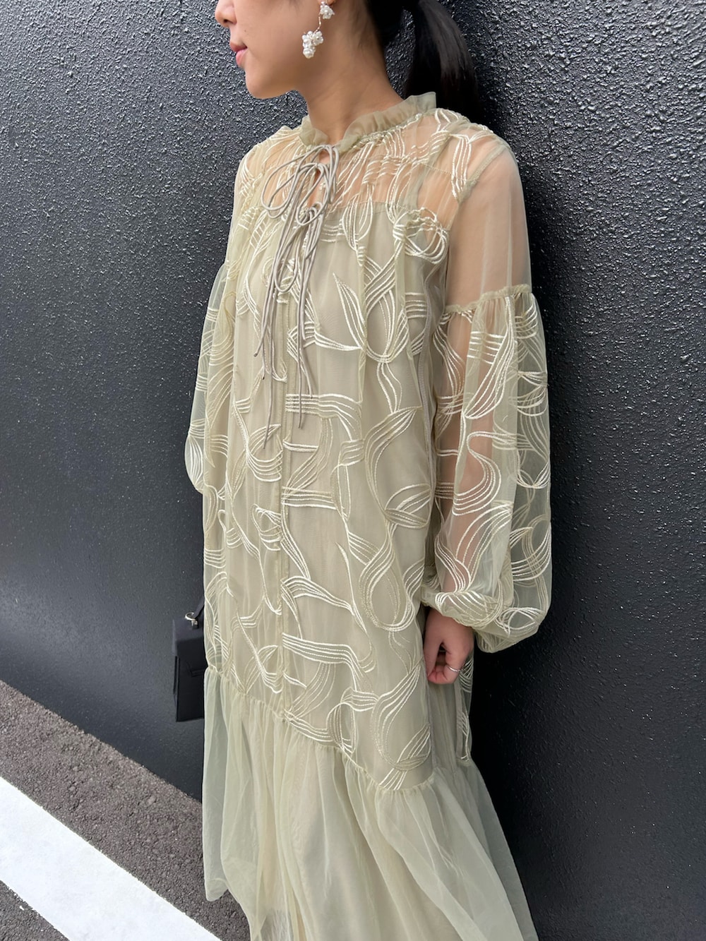 グリーン系のドレス、ブラック系のハンドバッグ、ブラック系のパンプスを着用したレディースの冬コーディネートの3枚目の写真