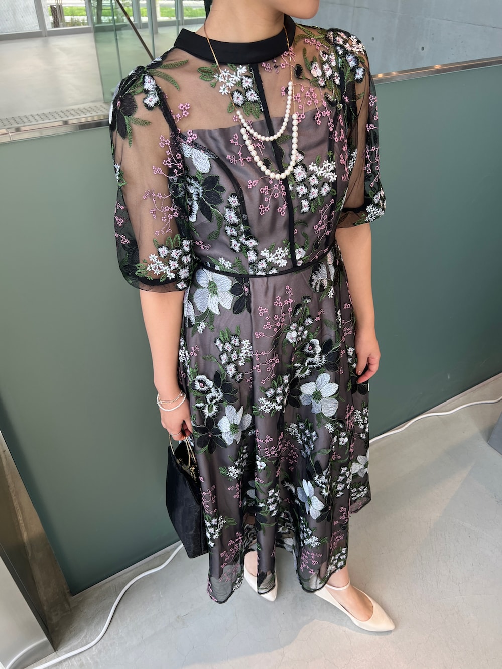 ベージュ系のハンドバッグ、ブラック系のドレス、ベージュ系のパンプスを着用したレディースの秋コーディネートの3枚目の写真