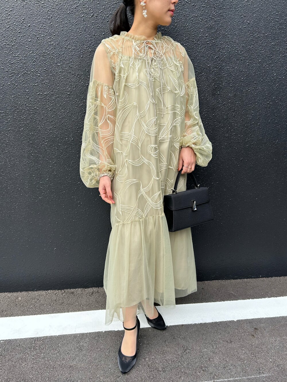 グリーン系のドレス、ブラック系のハンドバッグ、ブラック系のパンプスを着用したレディースの冬コーディネートの5枚目の写真