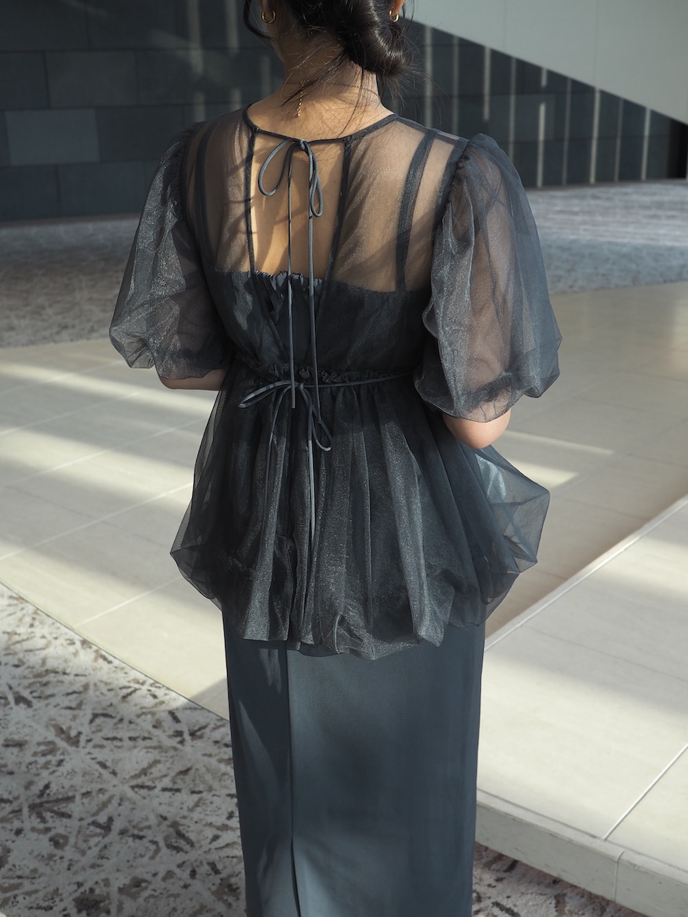 グレー系のドレス、シルバー系のクラッチバッグ、ベージュ系のパンプスを着用したレディースの冬コーディネートの5枚目の写真