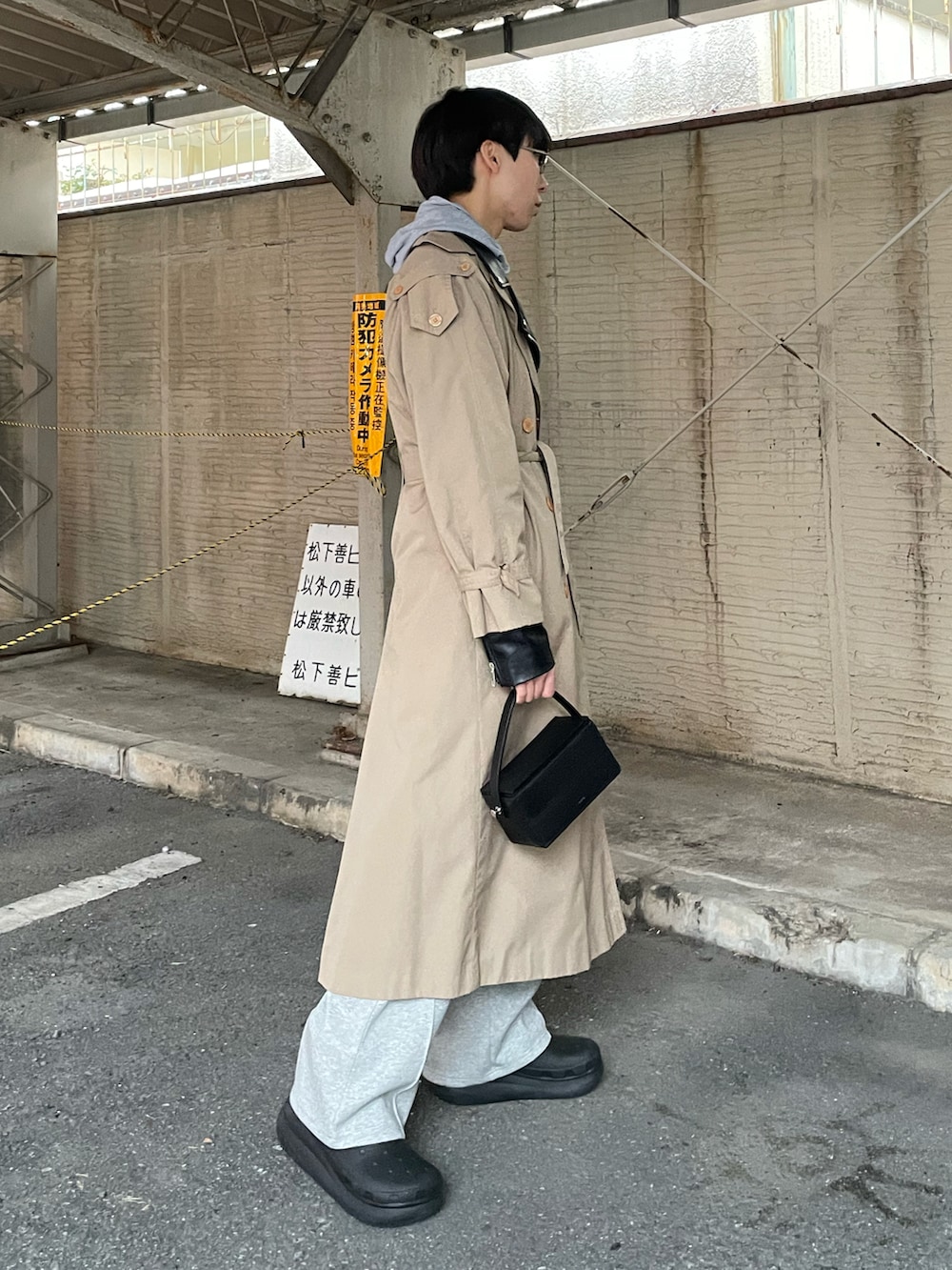 ブラック系のブーツ、ブラック系のショルダーバッグ、ベージュ系のトレンチコートを着用したメンズの冬コーディネートの2枚目の写真