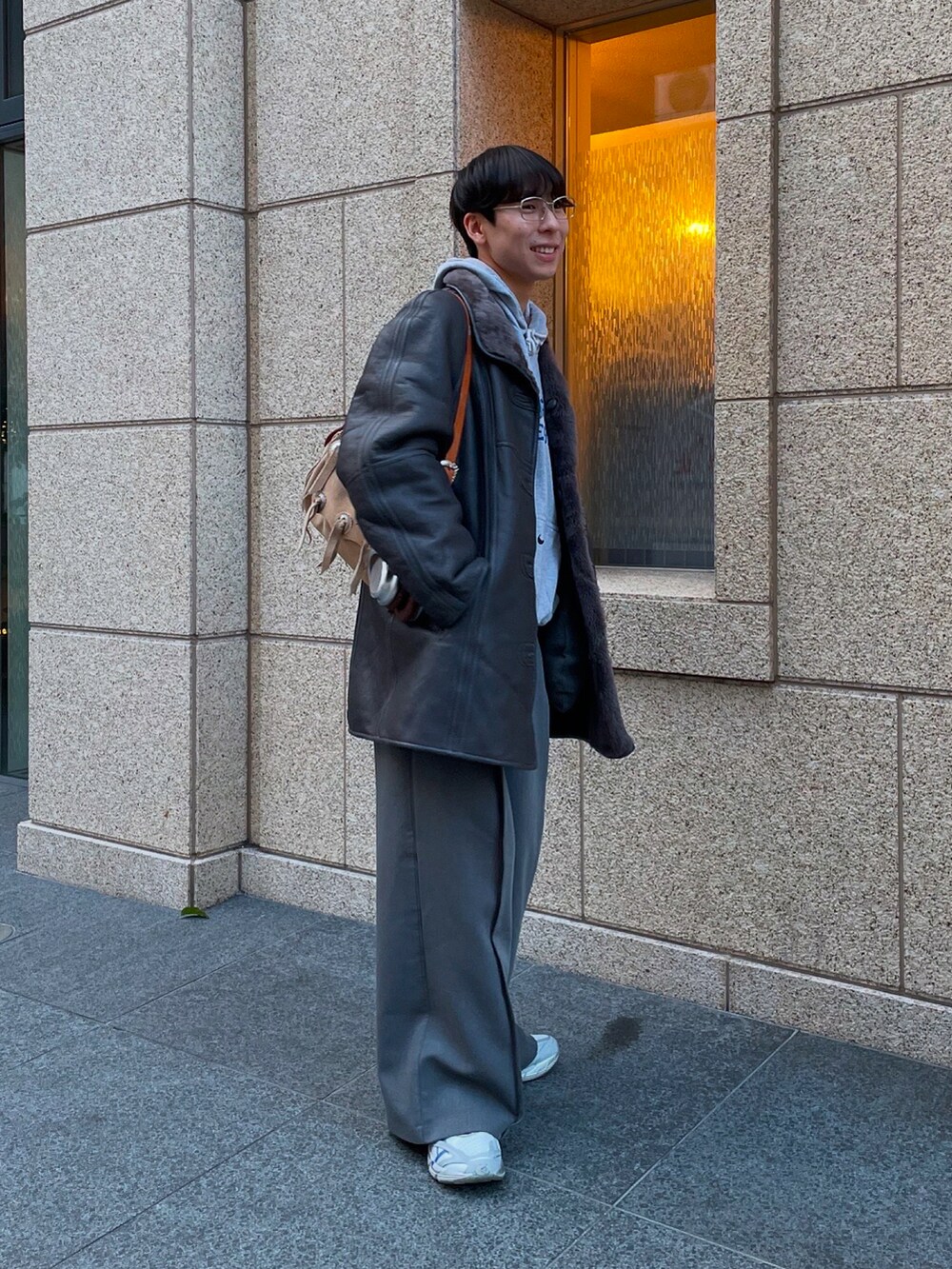 グレー系のスラックス、ホワイト系のスニーカー、グレー系のムートンコートを着用したメンズの冬コーディネートの2枚目の写真