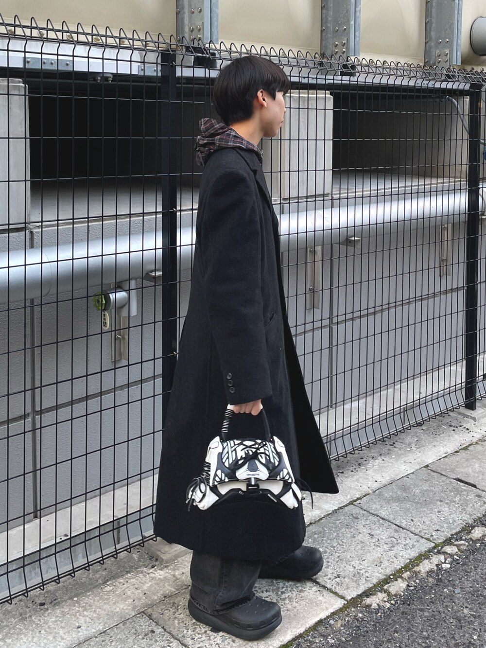 ブラック系のトレンチコート、ブラック系のパーカー、ブラック系のブーツを着用したメンズの冬コーディネートの2枚目の写真