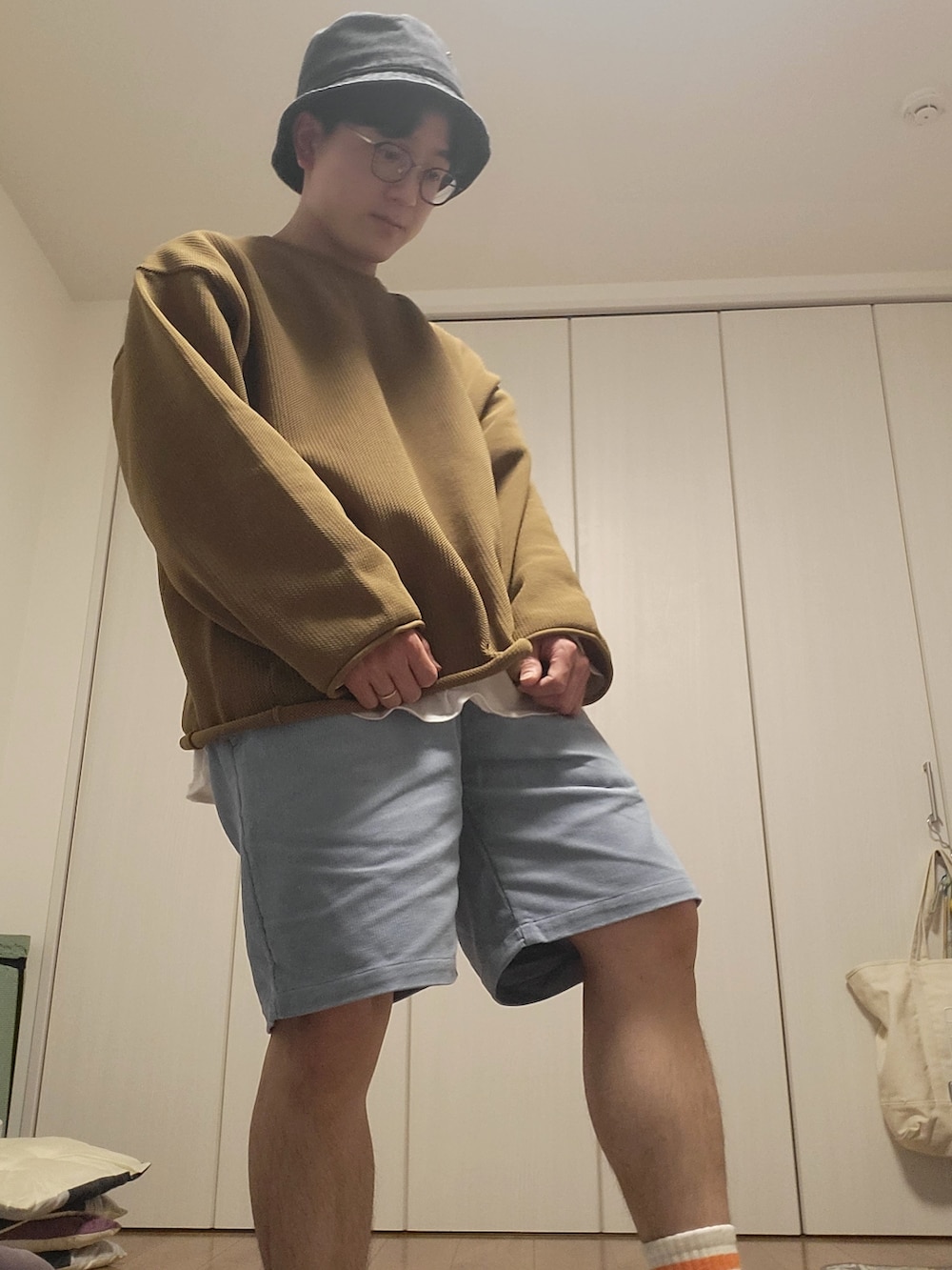 ベージュ系のニット/セーター、ブルー系のその他パンツ、ブラック系の帽子を着用したメンズの春コーディネートの2枚目の写真