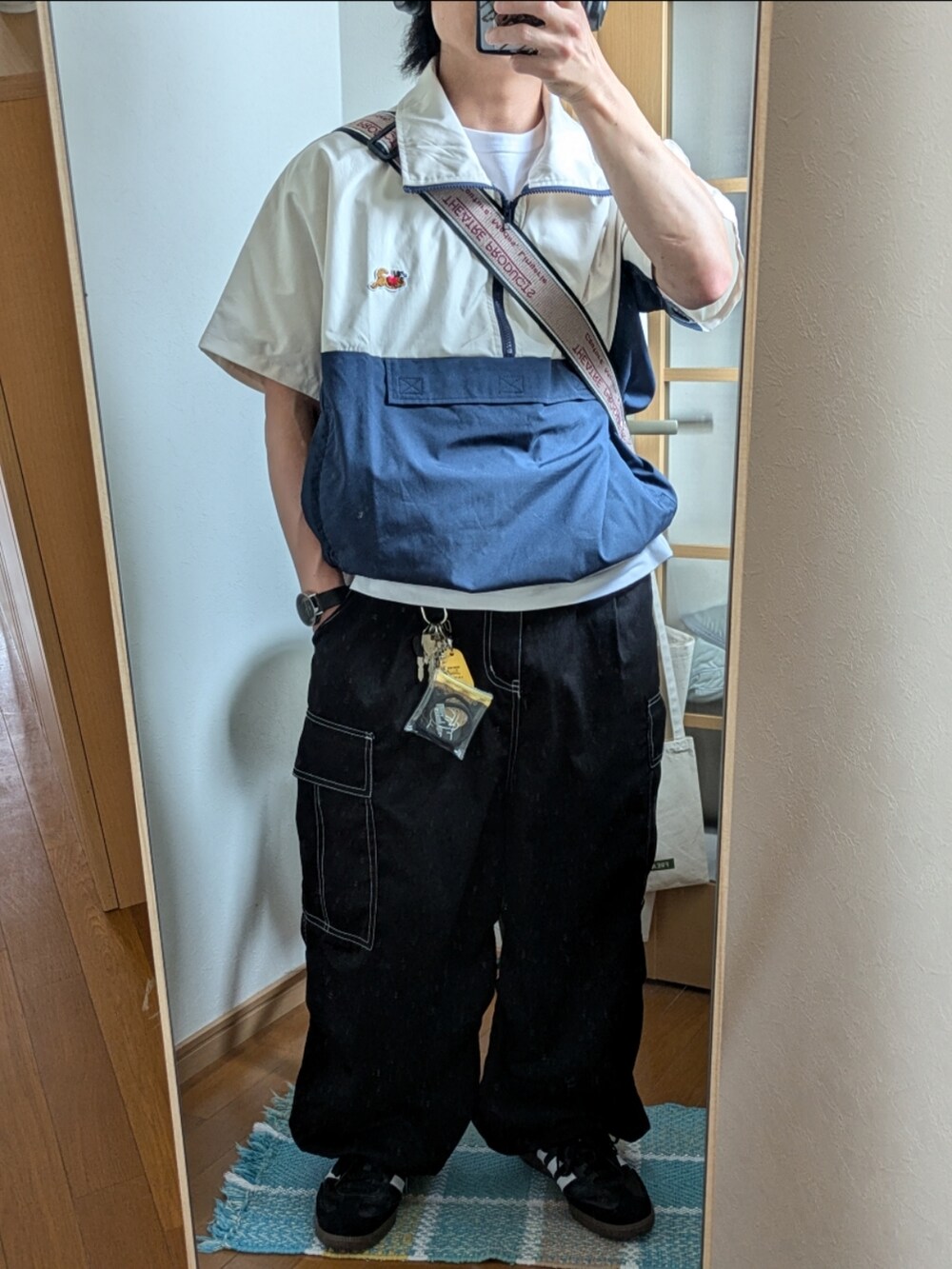 ブラック系のスニーカー、ブラック系のカーゴパンツ、ホワイト系のジャケット/アウターを着用したメンズの夏コーディネートの3枚目の写真