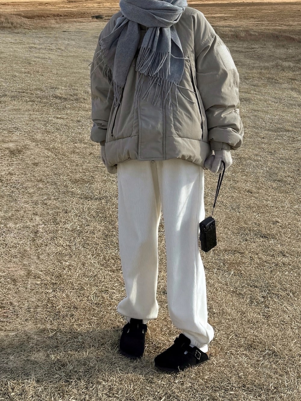 ホワイト系のパンツ、ブラック系のサンダル、グリーン系のダウンジャケット/コートを着用したレディースの冬コーディネートの2枚目の写真