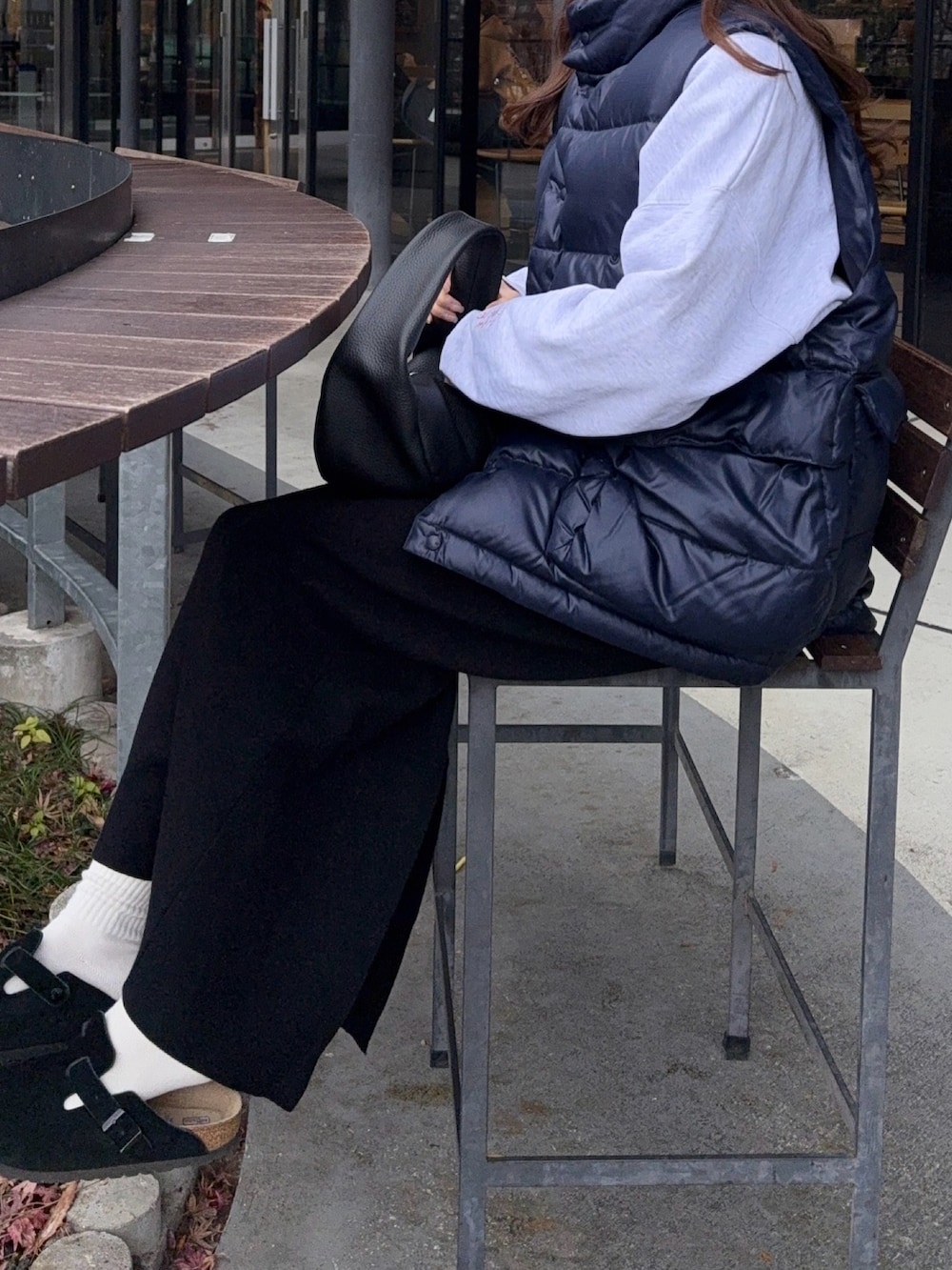 ブルー系のダウンベスト、ブラック系のスカート、ブラック系のサンダルを着用したレディースの冬コーディネートの2枚目の写真