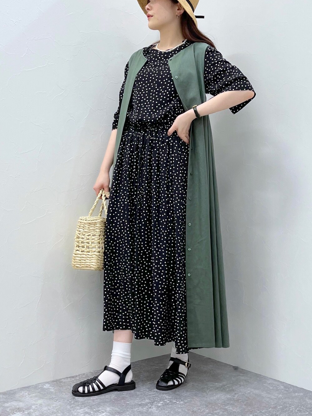 グリーン系のワンピース、ホワイト系のかごバッグ、ブラック系のサンダルを着用したレディースの春コーディネートの3枚目の写真