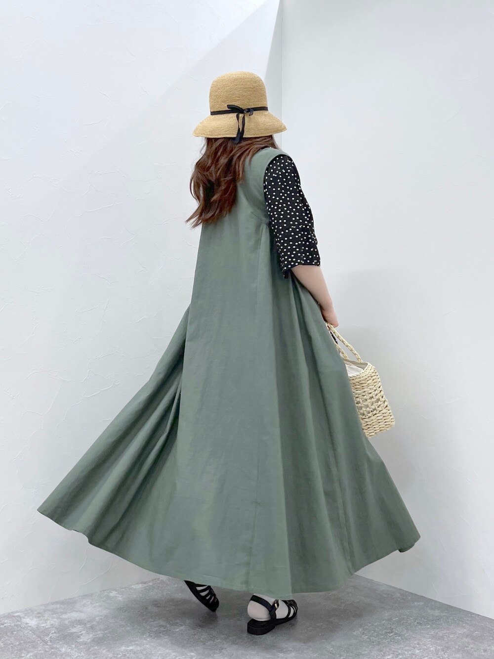 グリーン系のワンピース、ホワイト系のかごバッグ、ブラック系のサンダルを着用したレディースの春コーディネートの4枚目の写真