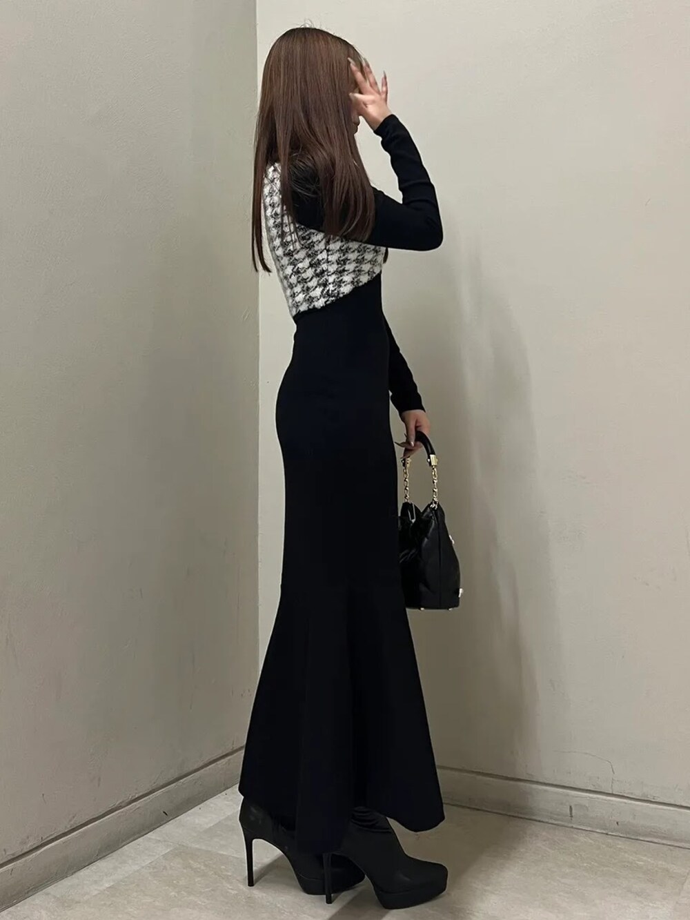 ブラック系のワンピース、ブラック系のブーツ、その他のハンドバッグを着用したレディースの秋コーディネートの2枚目の写真