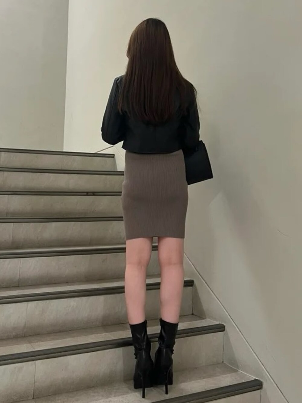 ブラック系のハンドバッグ、ブラック系のブーツ、ブラック系のライダースジャケットを着用したレディースの秋コーディネートの3枚目の写真