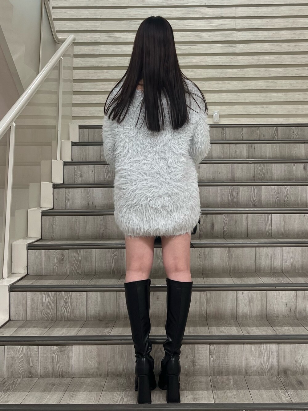 ブラック系のブーツ、ブラック系のハンドバッグ、グレー系のワンピースを着用したレディースの冬コーディネートの3枚目の写真