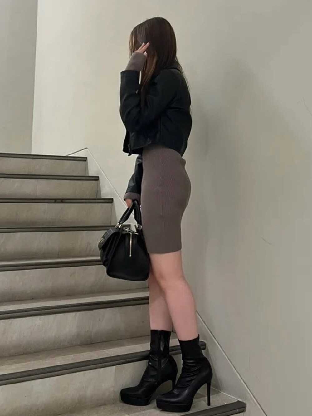 ブラック系のハンドバッグ、ブラック系のブーツ、ブラック系のライダースジャケットを着用したレディースの秋コーディネートの2枚目の写真