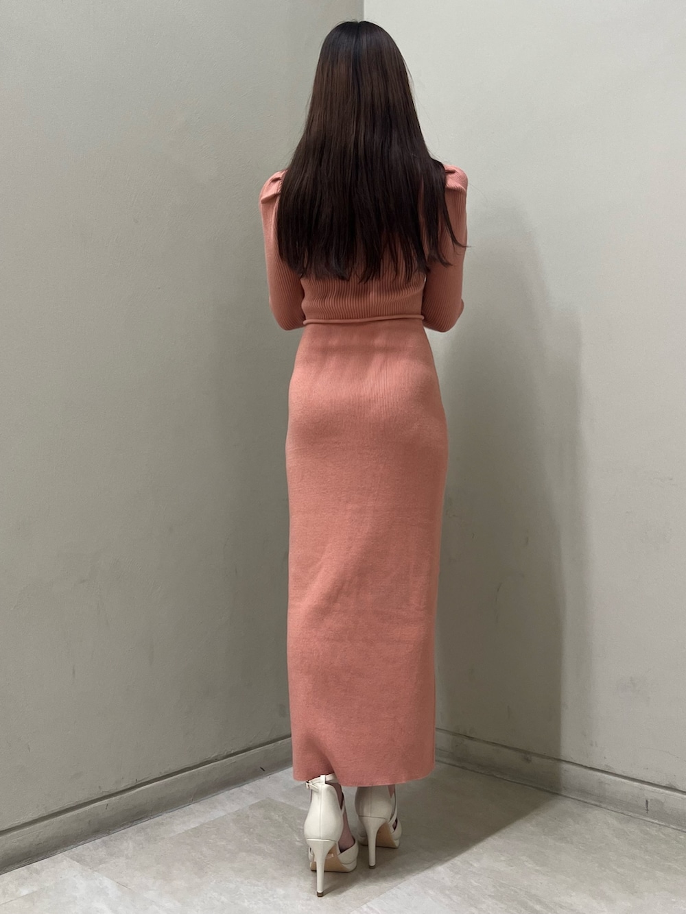 ホワイト系のパンプス、オレンジ系のワンピース、ゴールド系のネックレスを着用したレディースの冬コーディネートの3枚目の写真