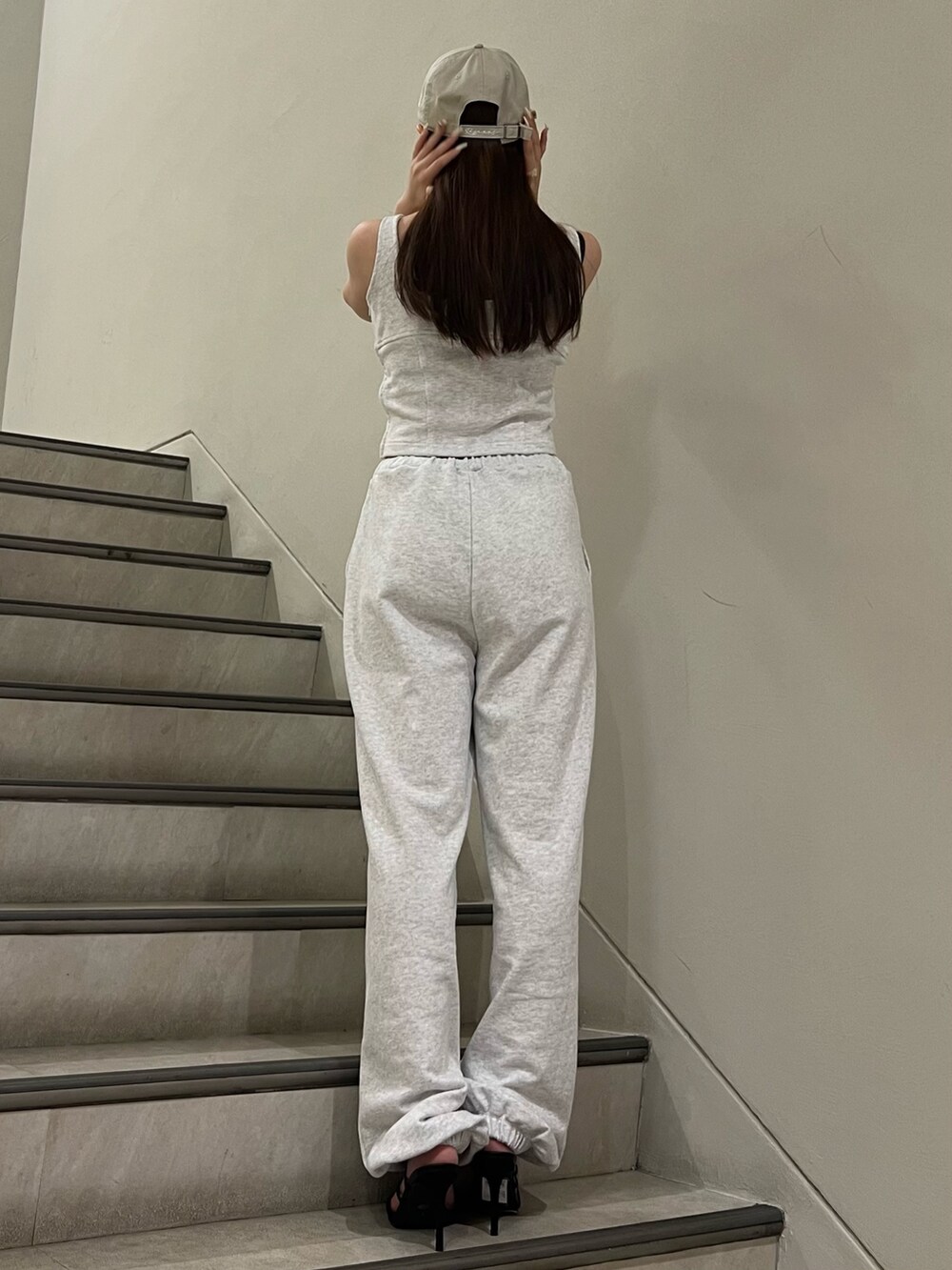 グレー系のタンクトップ、グレー系のスウェットパンツ、ブラック系のサンダルを着用したレディースの夏コーディネートの3枚目の写真