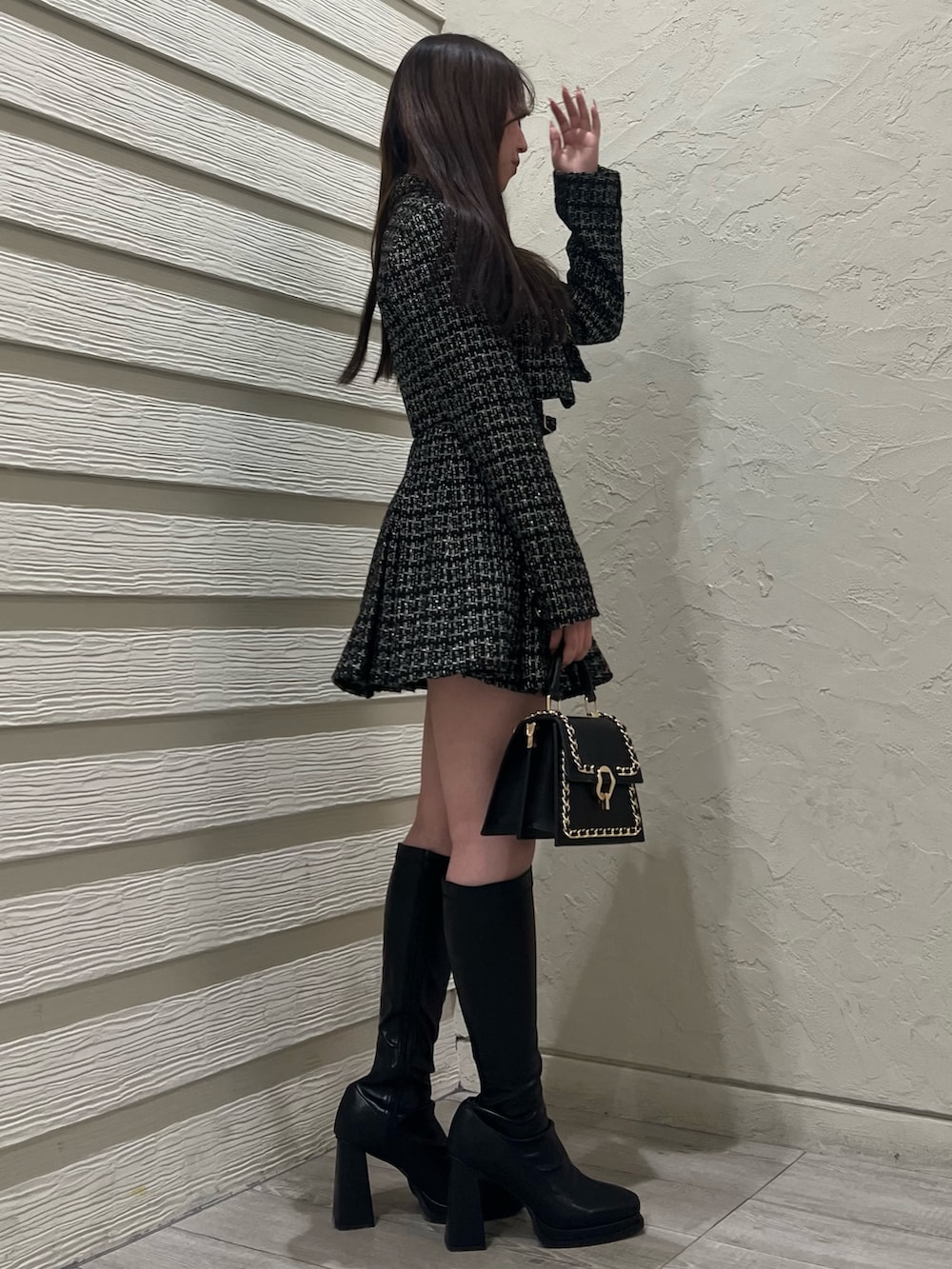 ブラック系のハンドバッグ、ブラック系のブーツ、ホワイト系のニット/セーターを着用したレディースの冬コーディネートの2枚目の写真