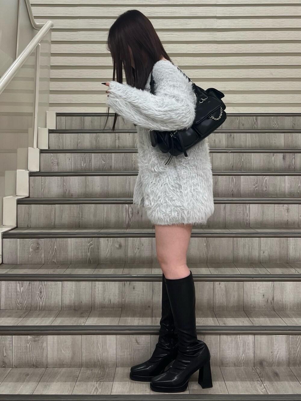 ブラック系のブーツ、ブラック系のハンドバッグ、グレー系のワンピースを着用したレディースの冬コーディネートの2枚目の写真