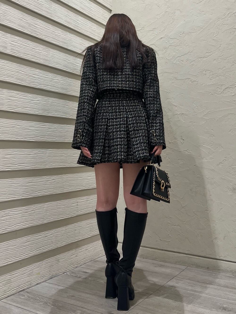 ブラック系のハンドバッグ、ブラック系のブーツ、ホワイト系のニット/セーターを着用したレディースの冬コーディネートの3枚目の写真