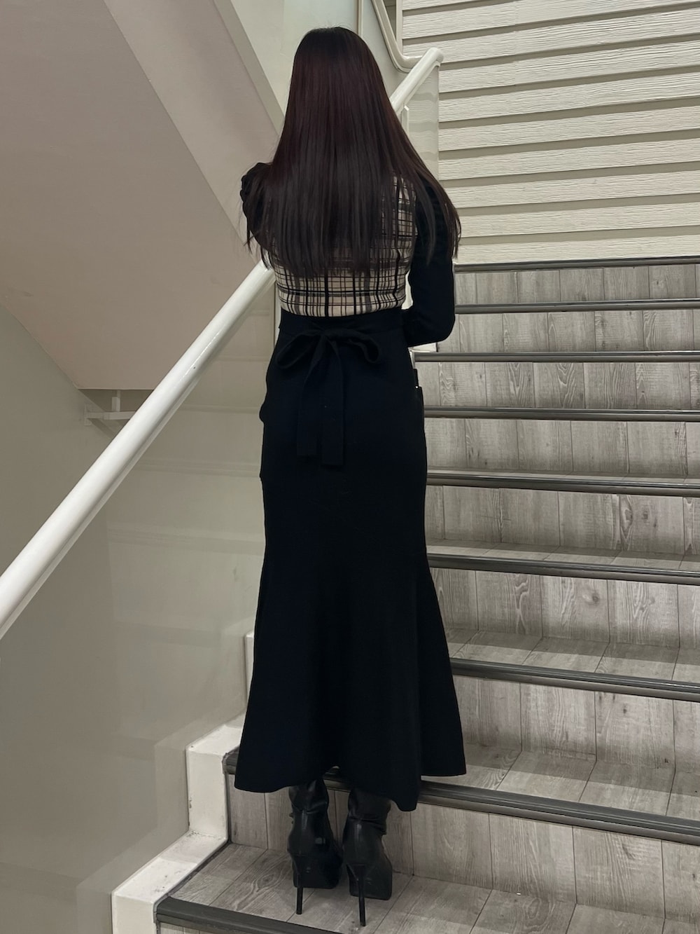 ブラック系のブーツ、ブラック系のワンピース、ブラック系のハンドバッグを着用したレディースの冬コーディネートの3枚目の写真