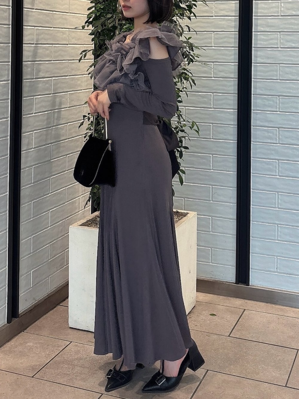 ブラック系のパンプス、グレー系のワンピース、ブラック系のハンドバッグを着用したレディースの秋コーディネートの2枚目の写真