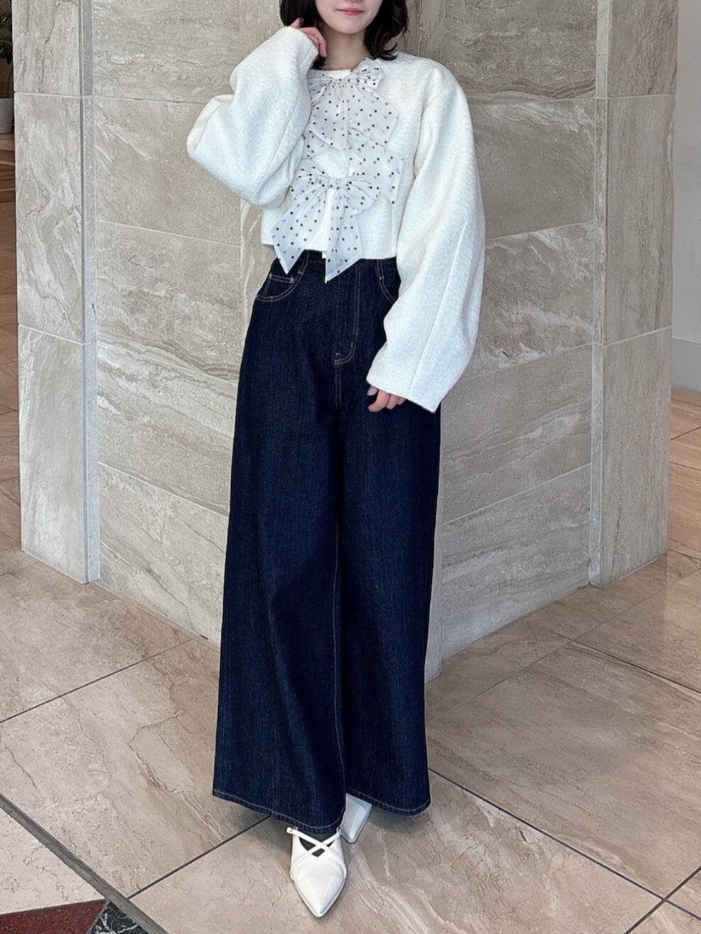 ホワイト系のパンプス、ブルー系のデニムパンツ、ホワイト系のブルゾンを着用したレディースの冬コーディネートの2枚目の写真