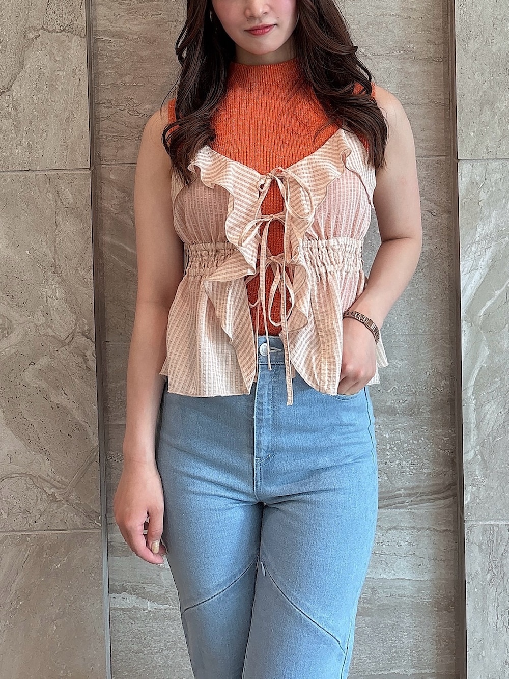 ブルー系のデニムパンツ、オレンジ系のニット/セーター、オレンジ系のキャミソールを着用したレディースの夏コーディネートの6枚目の写真