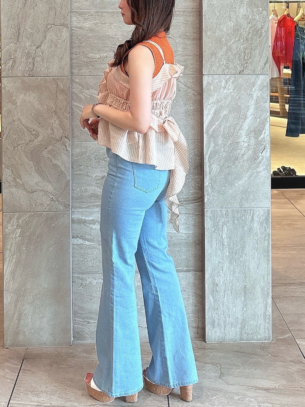 ブルー系のデニムパンツ、オレンジ系のニット/セーター、オレンジ系のキャミソールを着用したレディースの夏コーディネートの3枚目の写真