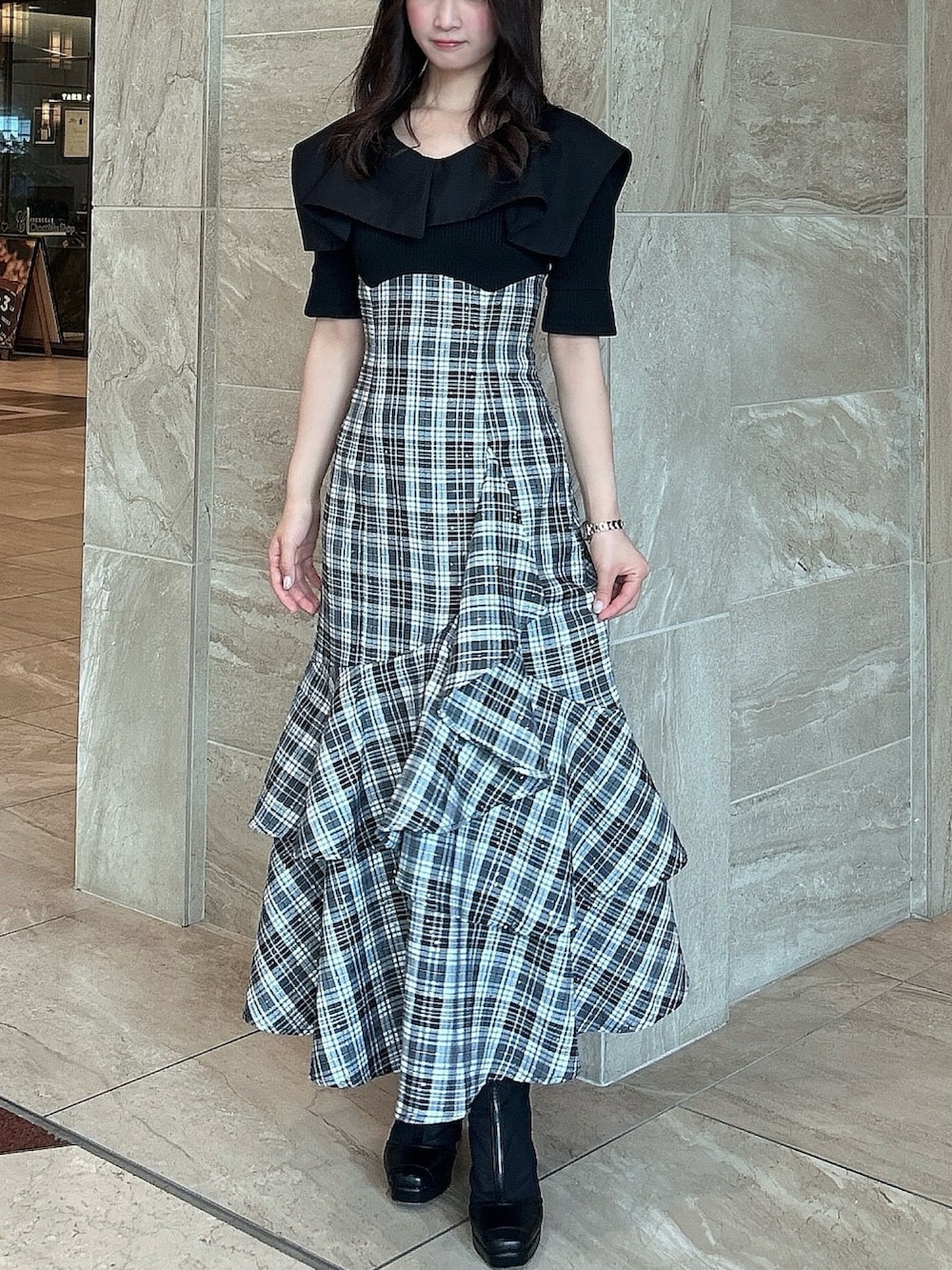 ブラック系のワンピース、ブラック系のブーツを着用したレディースの春コーディネートの2枚目の写真