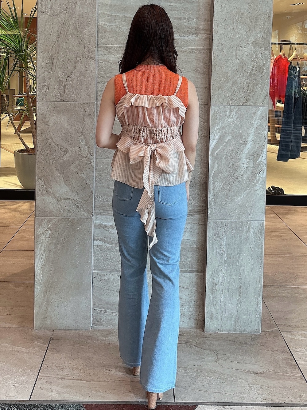 ブルー系のデニムパンツ、オレンジ系のニット/セーター、オレンジ系のキャミソールを着用したレディースの夏コーディネートの5枚目の写真