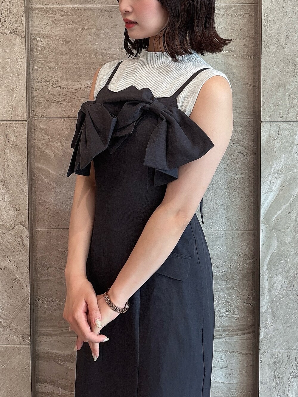 グレー系のワンピース、ブラック系のサンダル、ホワイト系のニット/セーターを着用したレディースの夏コーディネートの5枚目の写真