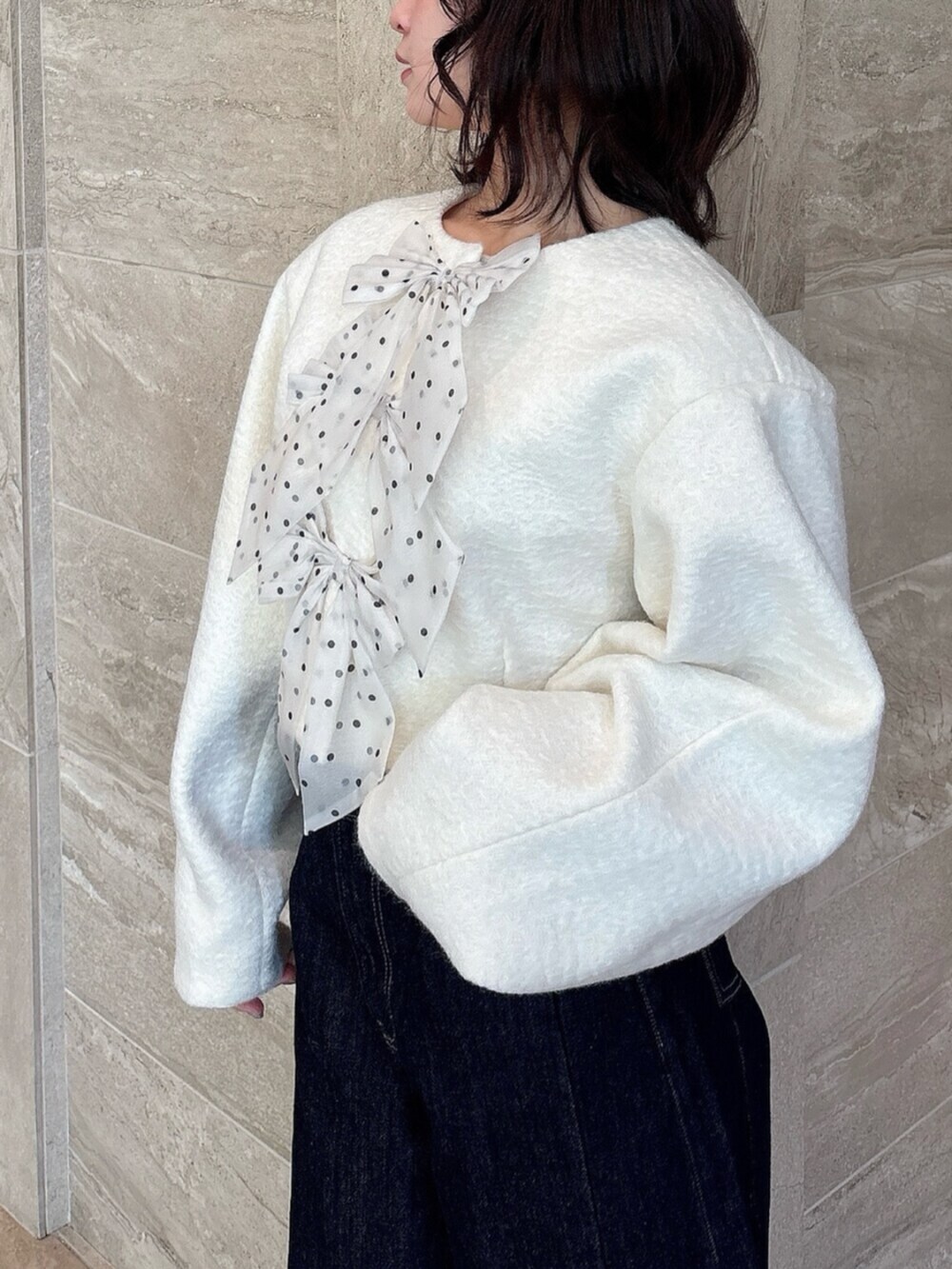 ホワイト系のパンプス、ブルー系のデニムパンツ、ホワイト系のブルゾンを着用したレディースの冬コーディネートの6枚目の写真