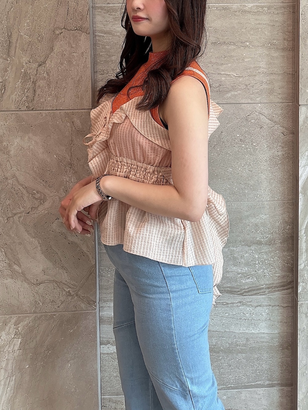 ブルー系のデニムパンツ、オレンジ系のニット/セーター、オレンジ系のキャミソールを着用したレディースの夏コーディネートの7枚目の写真