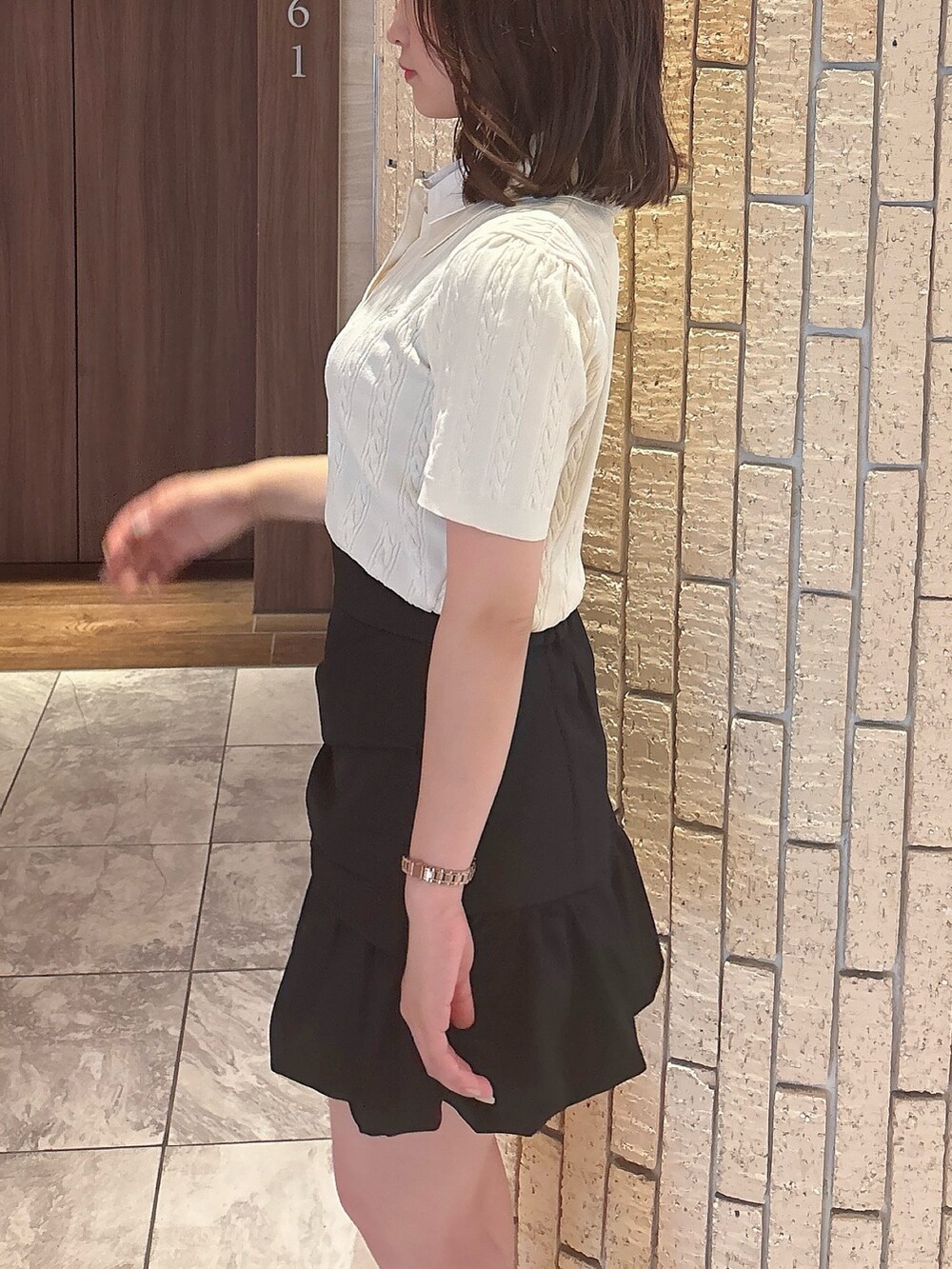 ブラック系のスカート、ホワイト系のニット/セーター、ブラック系のサンダルを着用したレディースの夏コーディネートの6枚目の写真