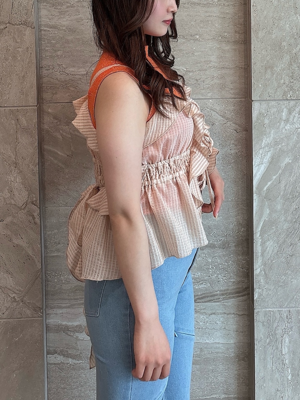 ブルー系のデニムパンツ、オレンジ系のニット/セーター、オレンジ系のキャミソールを着用したレディースの夏コーディネートの8枚目の写真