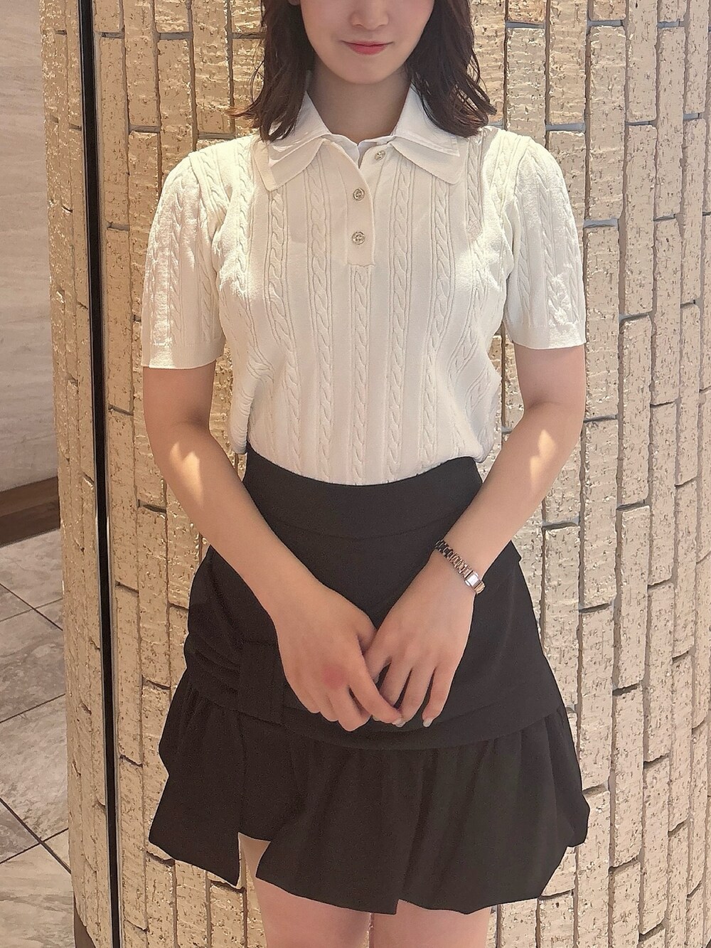 ブラック系のスカート、ホワイト系のニット/セーター、ブラック系のサンダルを着用したレディースの夏コーディネートの5枚目の写真