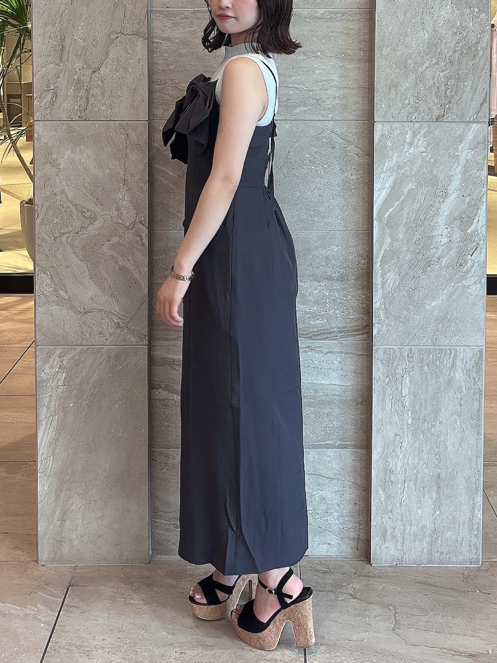 グレー系のワンピース、ブラック系のサンダル、ホワイト系のニット/セーターを着用したレディースの夏コーディネートの2枚目の写真