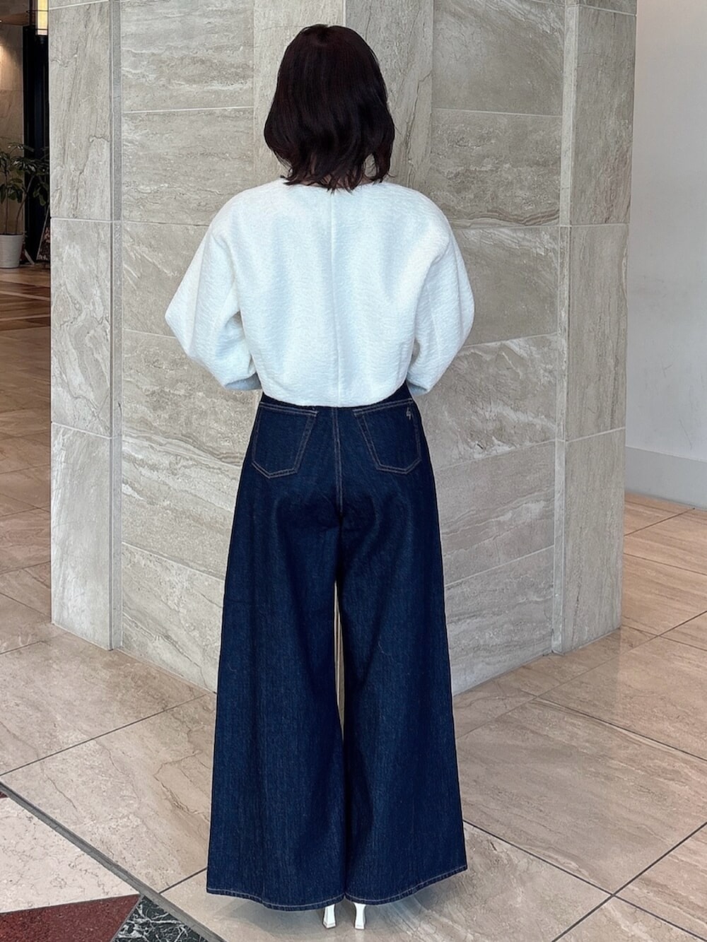 ホワイト系のパンプス、ブルー系のデニムパンツ、ホワイト系のブルゾンを着用したレディースの冬コーディネートの4枚目の写真