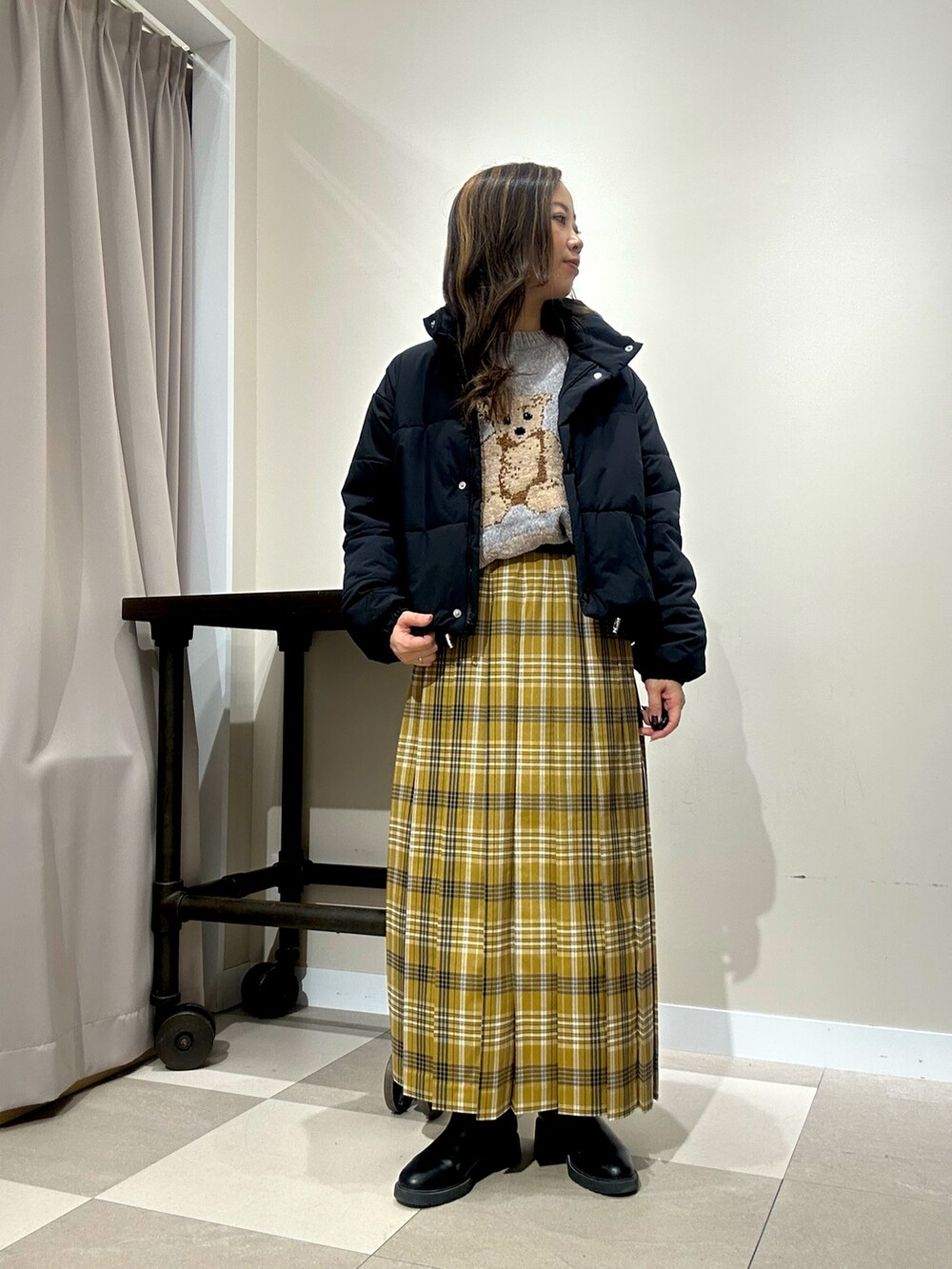 グレー系のニット/セーター、イエロー系のスカートを着用したレディースの冬コーディネートの2枚目の写真